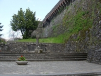 La fontana in pietra, sulla destra si intravede la Rocca